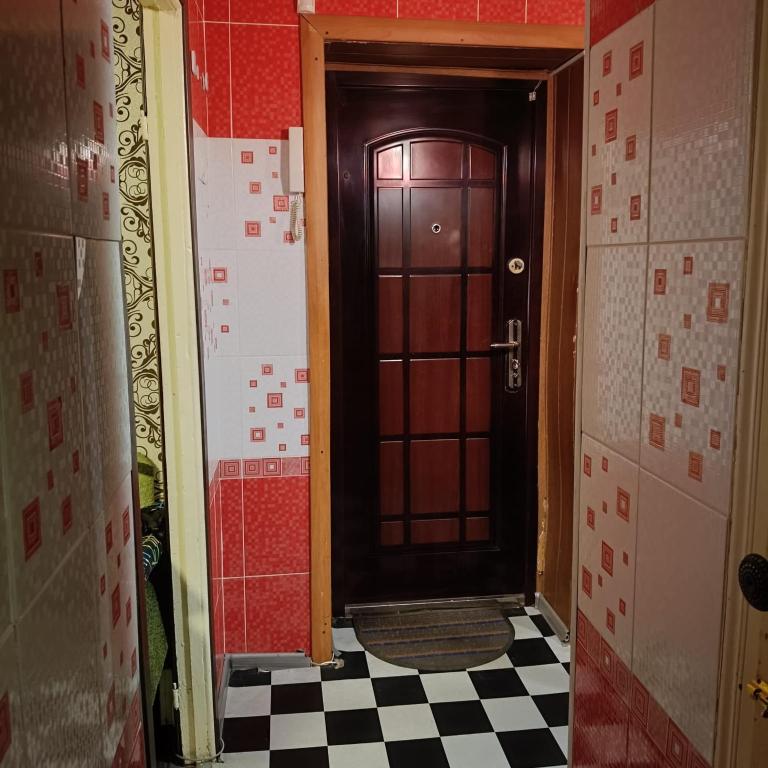 a hallway with a brown door and a checkered floor at Квартира in Sumy