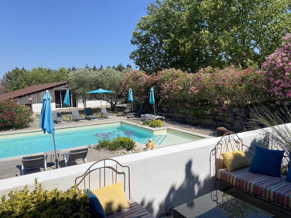 a swimming pool with a couch and umbrellas next to it at Gîte Carcassonne le Relais de la Cavayere in Carcassonne