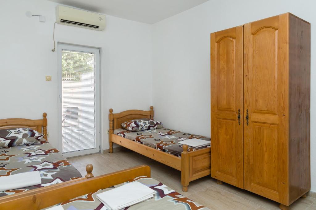 a bedroom with two beds and a wooden cabinet at Apartmani Šarkinović in Sutomore