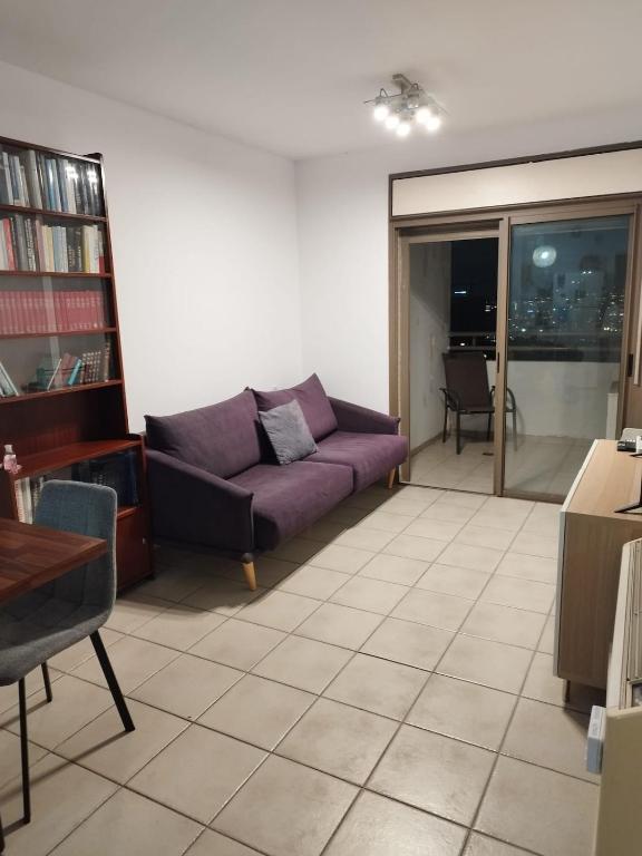 a living room with a purple couch and a window at Small, well-equipped apartment, Chabat elevator in Giv‘at Shemuʼel