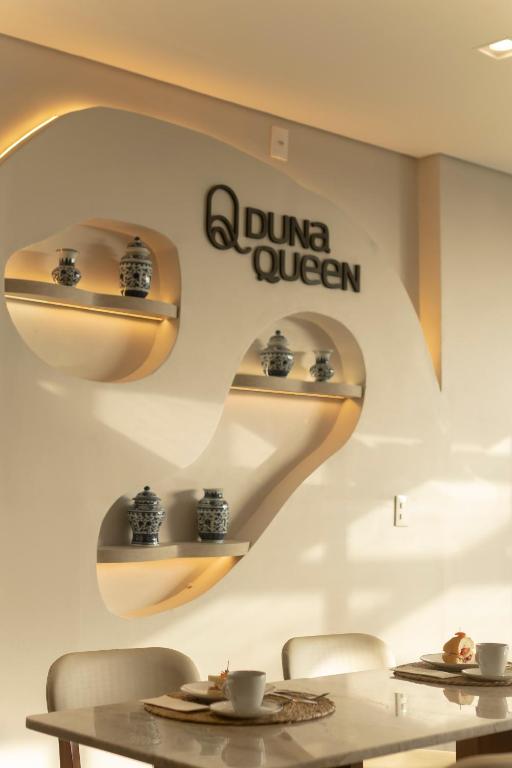 ein Esszimmer mit zwei Tischen und einem Schild an der Wand in der Unterkunft Duna Queen Hotel Conceito in Barreirinhas
