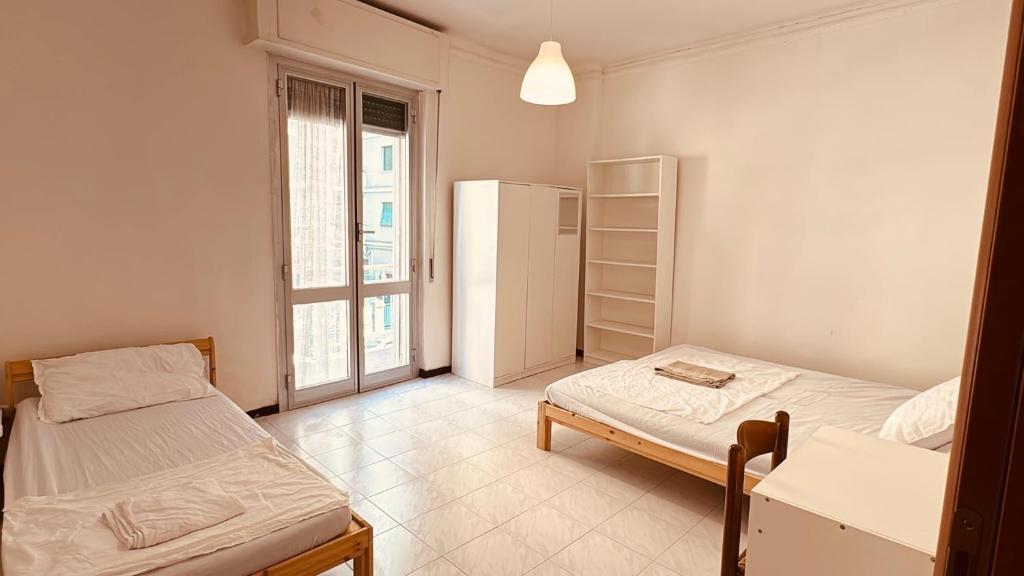 ein Zimmer mit zwei Betten und einem Kühlschrank in der Unterkunft Double and Triple Rooms near Principe Station Shared Bathroom in Genua