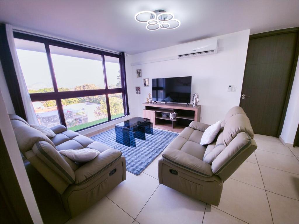 a living room with two couches and a flat screen tv at Bostor Apartament in San Salvador