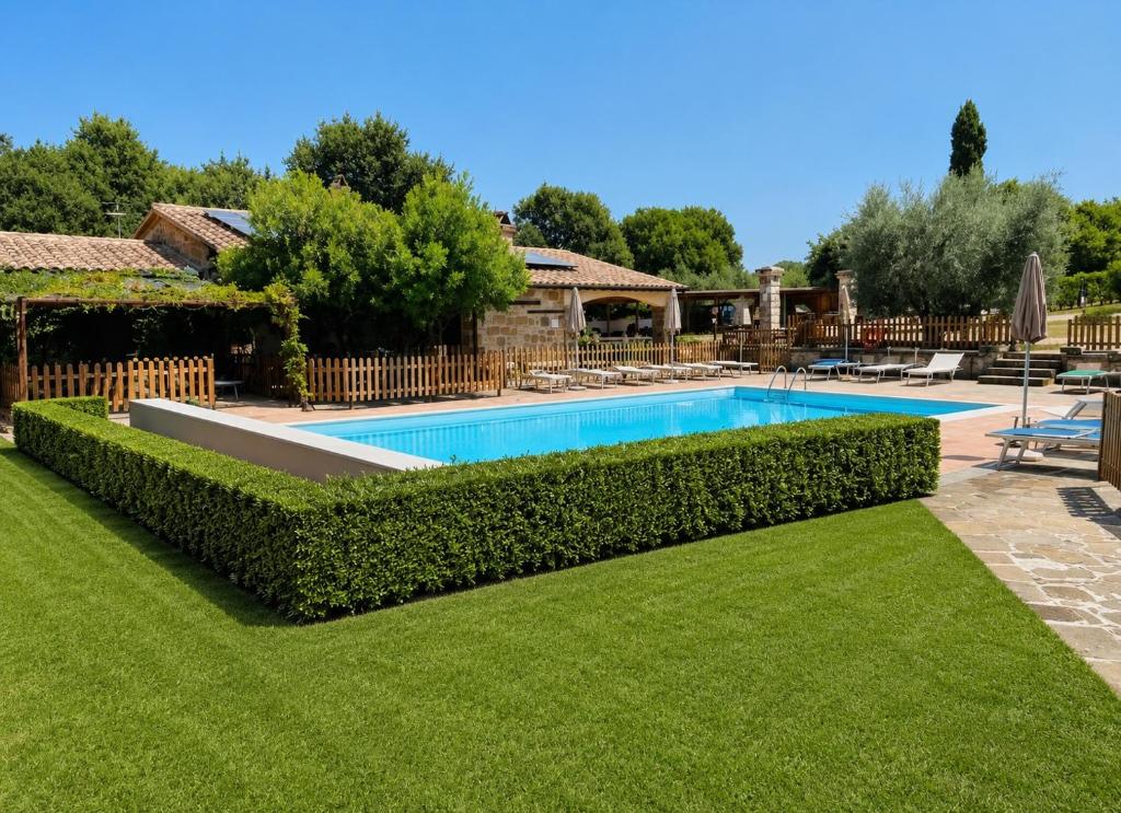 a swimming pool in a yard with a hedge at Agriturismo Eco-Bio Villa Vacasio in Pitigliano