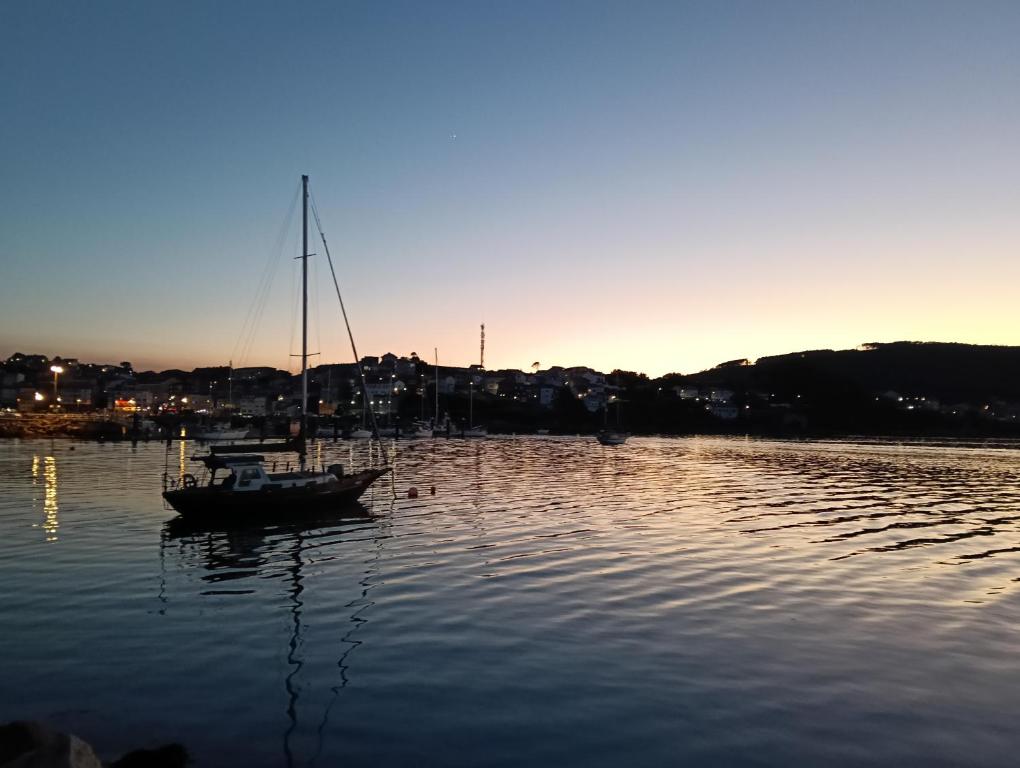 a boat sitting in the water at sunset at Piso Gallega in Finisterre