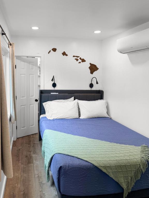 a bedroom with a bed with blue sheets and birds on the wall at Hibiscus Hale - Perfect for 2! in Waialua