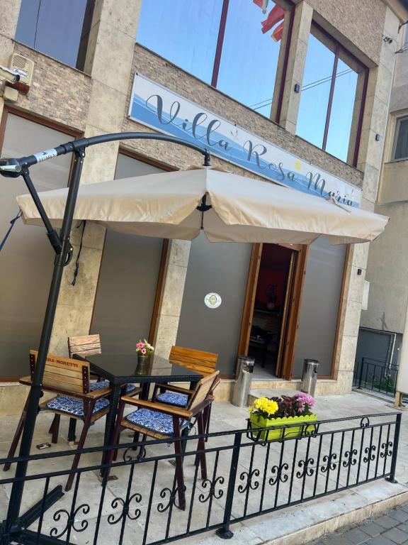 a table and chairs under an umbrella on a balcony at Vila Rosa Maria in Mangalia