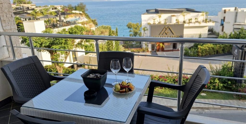 a table with a plate of food and wine glasses on a balcony at Marina Chic Apartment in Vlorë