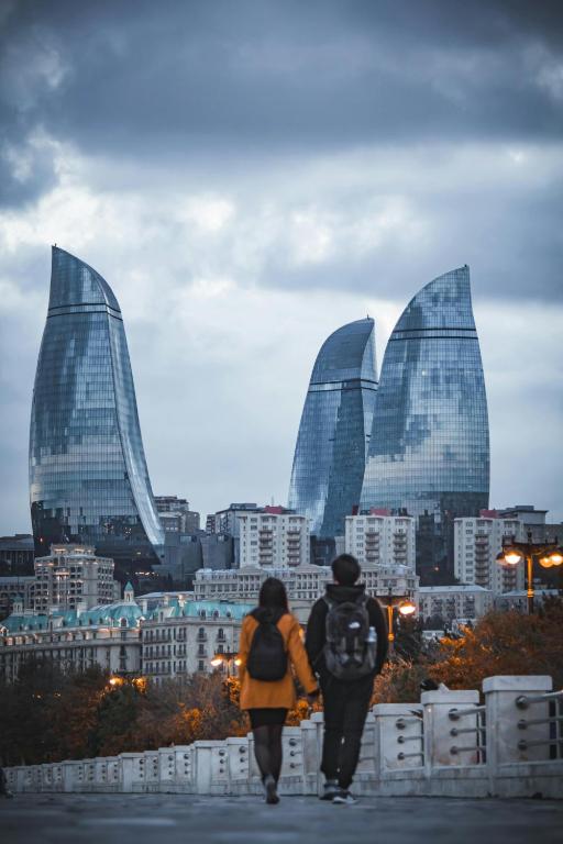two people walking down a bridge in front of a city at KING City Center Hostel in Baku