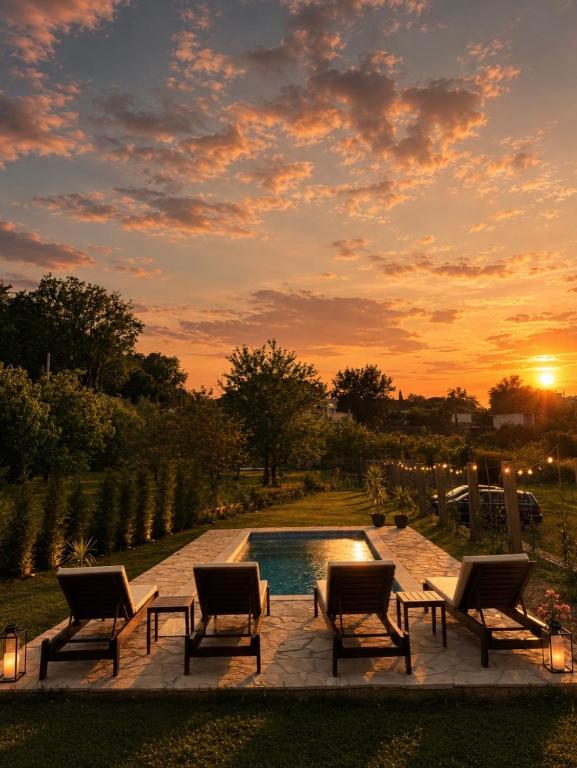 a pool with chairs and a sunset in the background at Maison Des Oliviers in Herceg-Novi