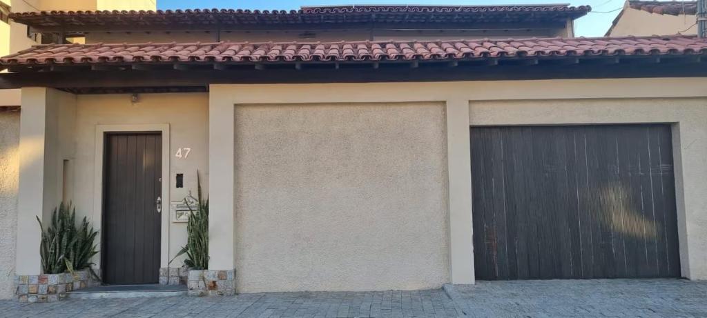 a house with two garage doors in front of it at Quarto Pernoite Costa do Sol in Macaé