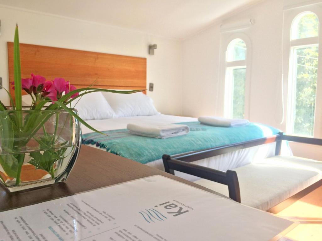 um quarto com duas camas e uma mesa com um vaso de flores em Kai Bed and Breakfast em Algarrobo