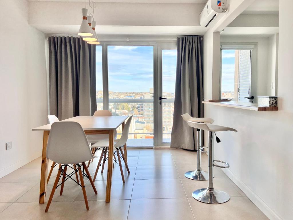 a dining room with a table and chairs and a window at Punta Flecha in Puerto Madryn