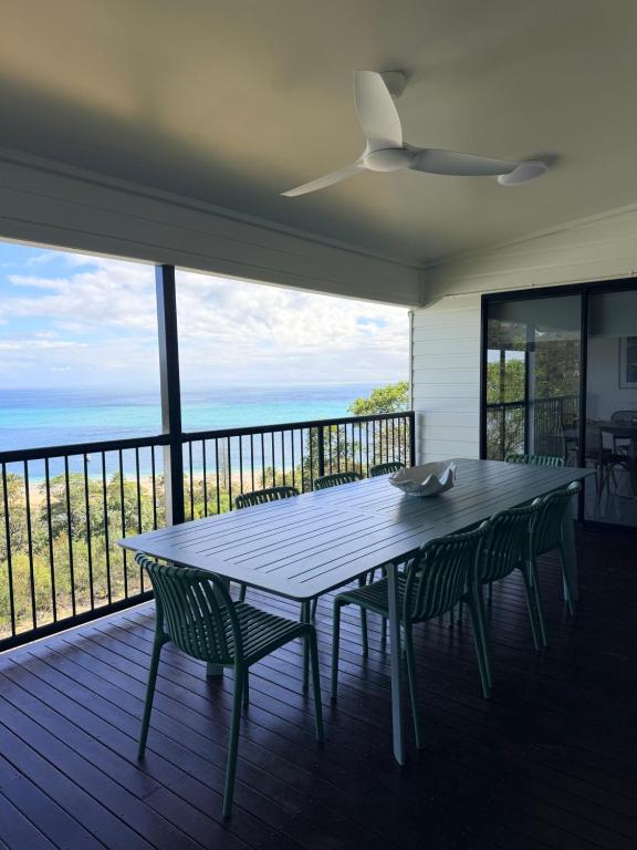 a table and chairs on a porch with a view of the ocean at The Dune House in Tangalooma