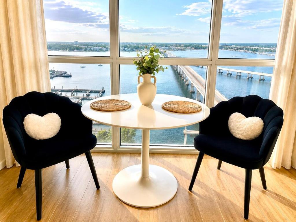 a table with two chairs and a vase on it in front of a window at The Caloosa Retreat in Fort Myers