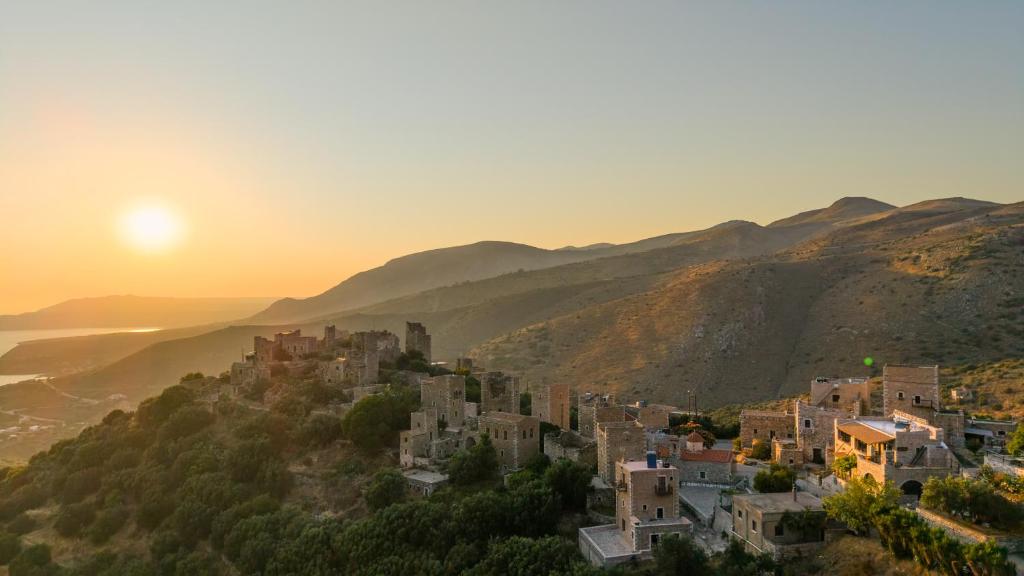 a village on a hill with the sun setting at Aspalathos guest rooms in Vathia