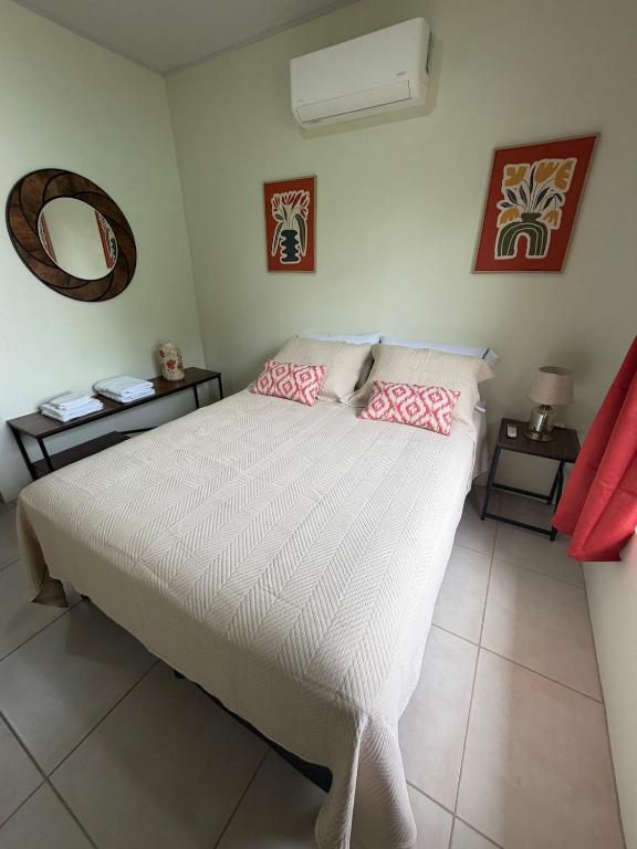 a bedroom with a white bed with pink pillows at Studio confort Uvita in Uvita