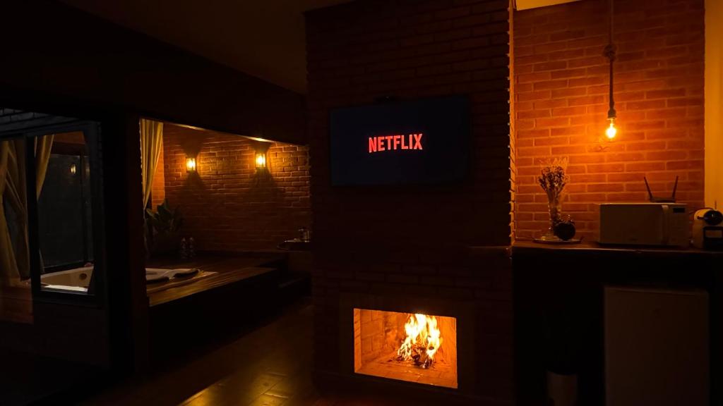 a room with a fireplace with a lit up sign at Chalé Raízes in Joanópolis