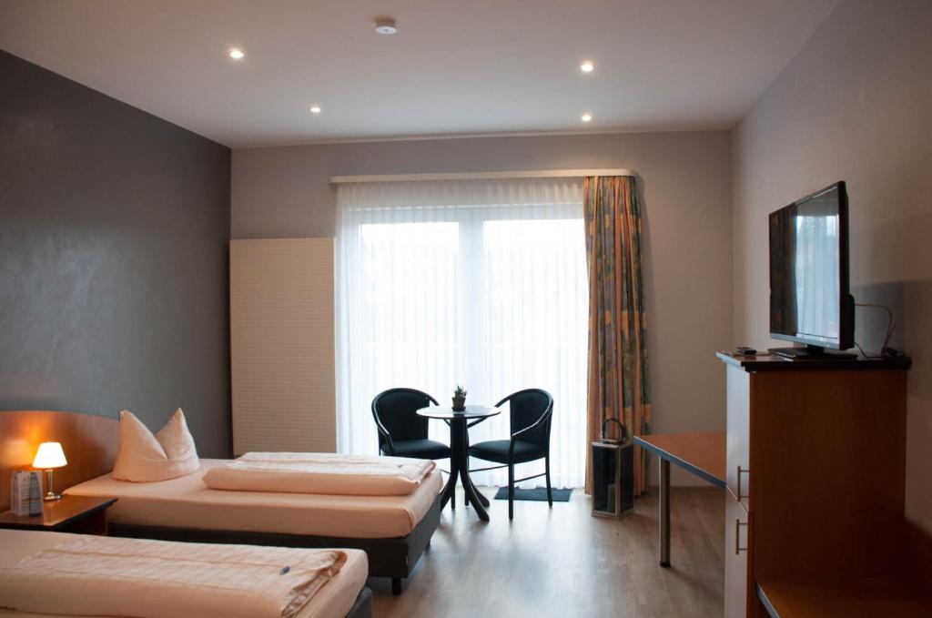 een hotelkamer met 2 bedden, een tafel en een raam bij Hotel Stadt Püttlingen in Püttlingen