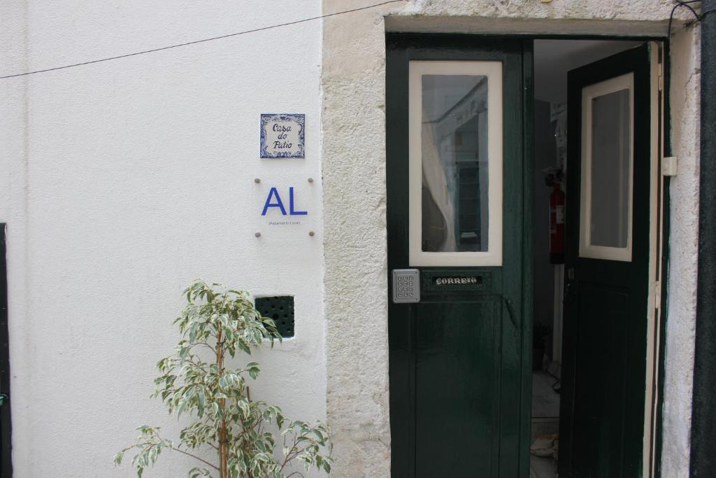 a building with a green door and a plant at Casa do Pátio in Lisbon