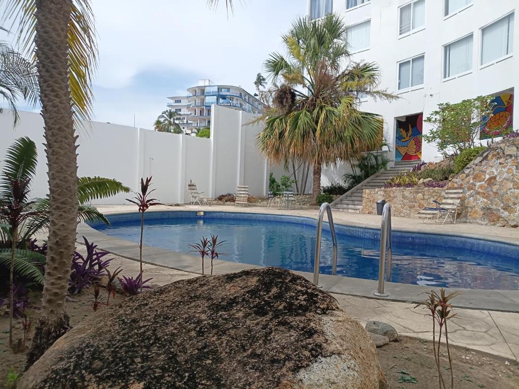 a swimming pool with a palm tree and a building at Sierra 5 in Acapulco