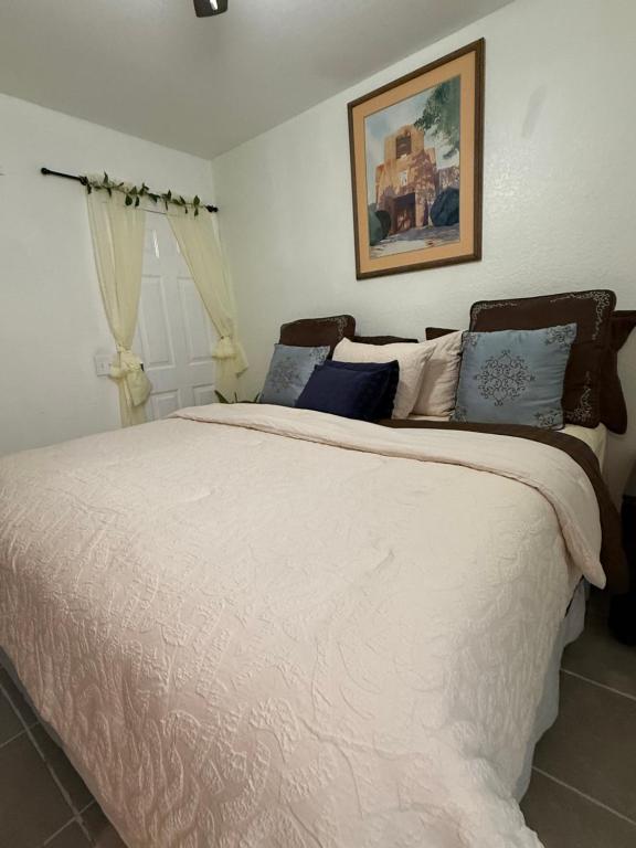 a bedroom with a large bed with white sheets and blue pillows at Serenity Garden Studio with Pool in Naples