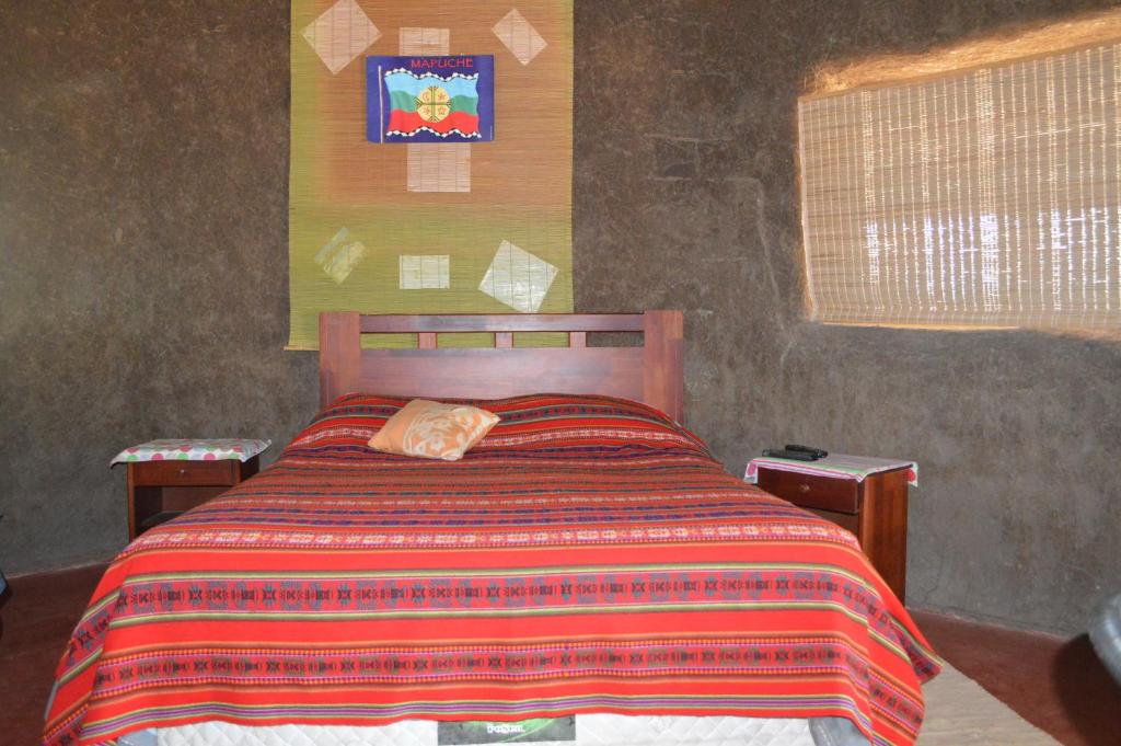 a bedroom with a bed with a striped comforter at Coyunche Cabañas y Camping Laja & San Rosendo in Laja