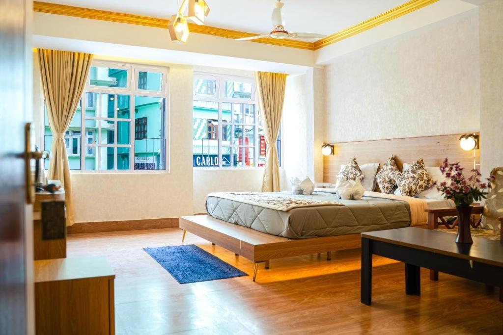 a bedroom with a bed and a table and a window at Hotel The Dzong ! Gangtok in Gangtok