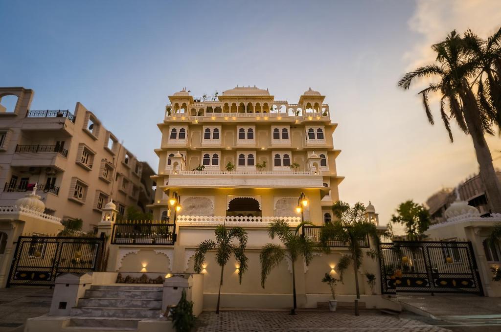 a large building with palm trees in front of it at Tripli Regalia Mayur Palace in Udaipur
