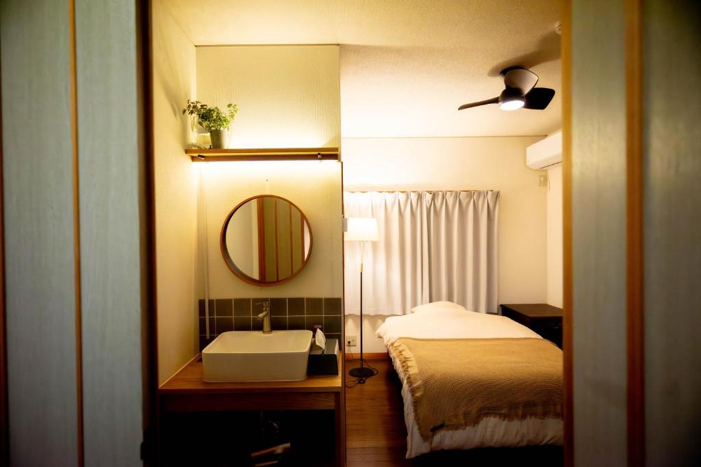 a bathroom with a bed and a sink and a mirror at Nomachi Villa in Kanazawa