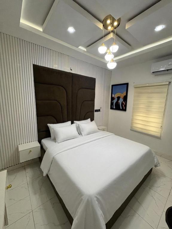 a bedroom with a large white bed with a large headboard at Hog Inn Hotel in Benin City