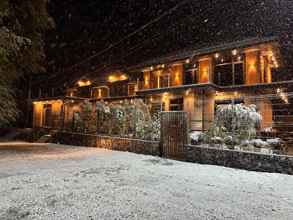 a house covered in snow at night at Zarechnoe Guest House in Tash-Tyube