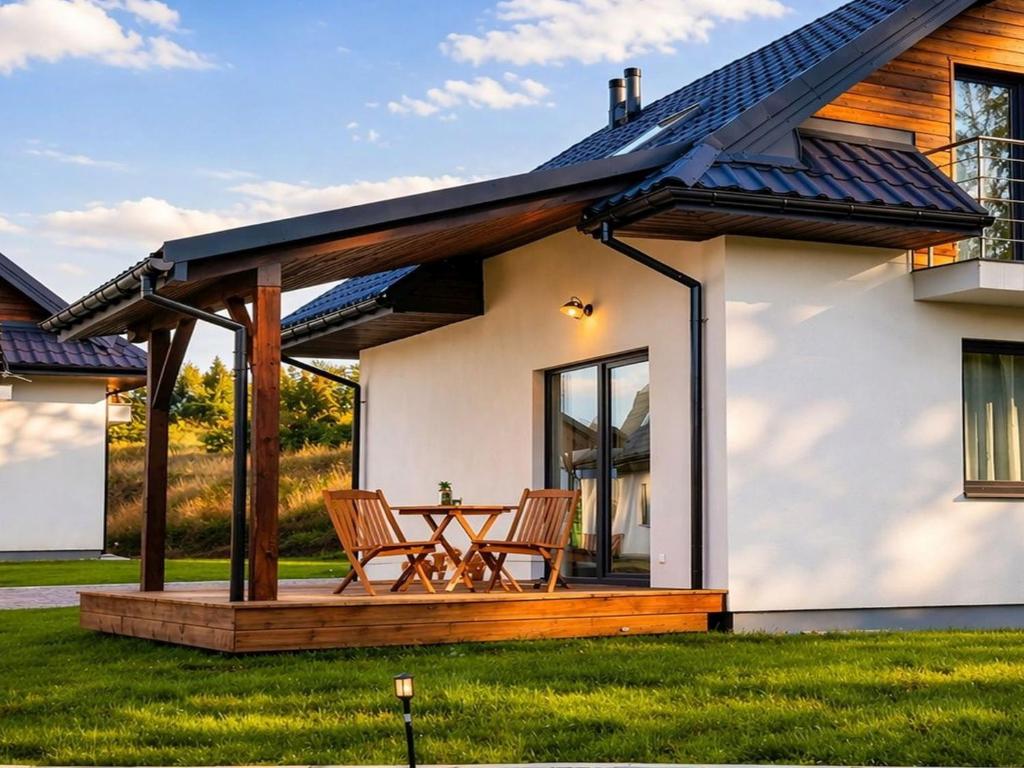 a house with a deck with two chairs at Panskiemisie Domki Całoroczne sauna jacuzzi in Wetlina