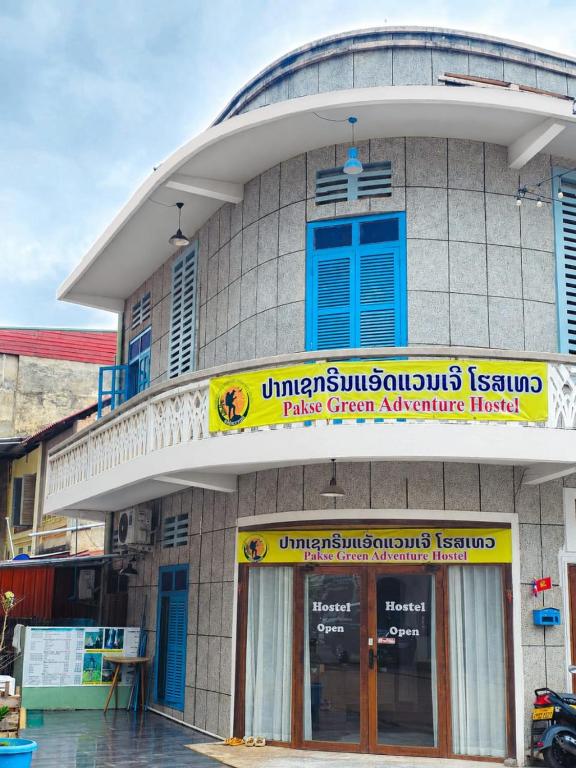 a building with a yellow and blue sign on it at Pakse Green Adventure Hostel Two in Pakse
