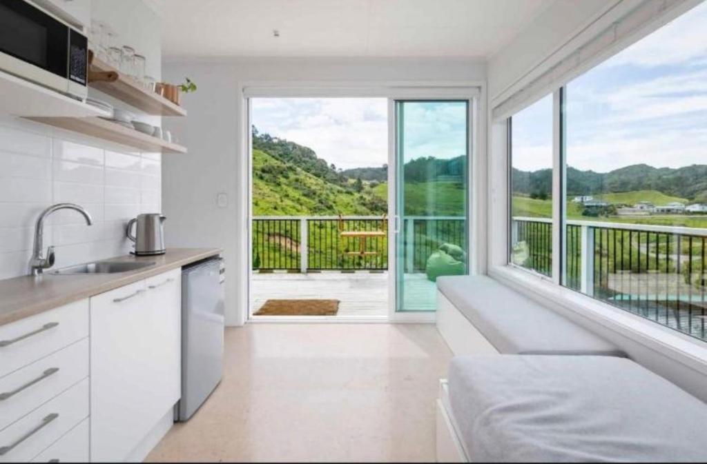 a kitchen with white cabinets and a large window at Tohora View in Waihi Beach