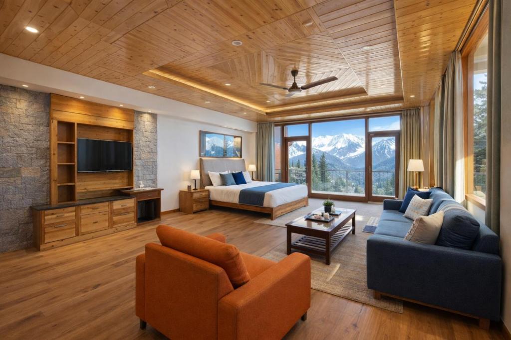 a living room with a couch and a bed and a television at LN Grand Premium & Luxury Suites, Manali in Manāli