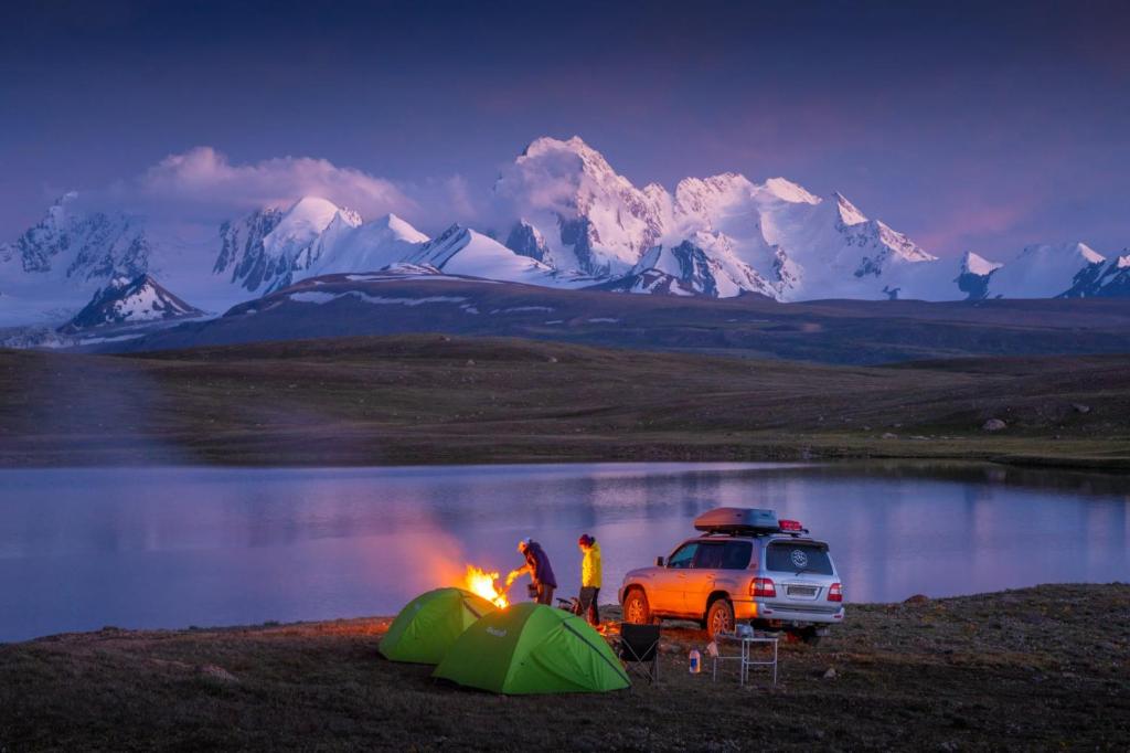 two people standing around a campfire and a tent and a car at Family nest in Kochkorka
