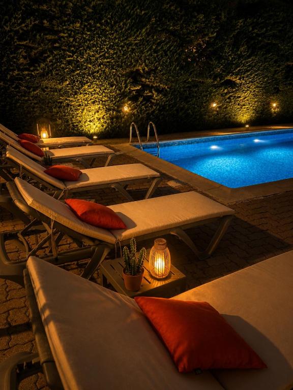 a row of lounge chairs next to a pool at night at Hotel Cayrons Vence & St Paul de Vence in Vence