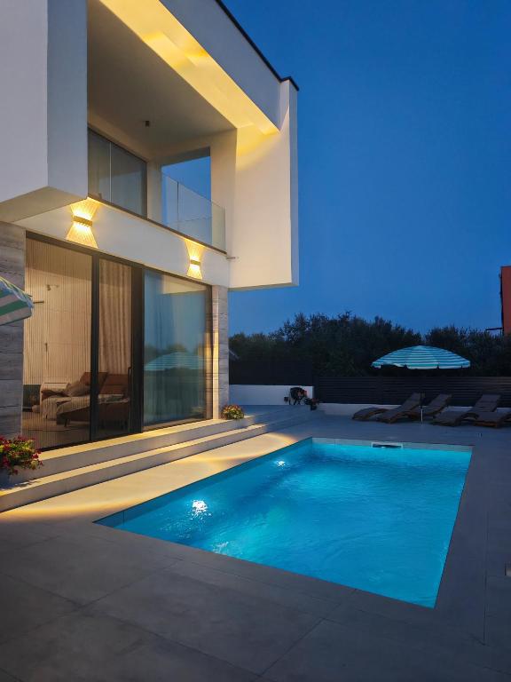 a swimming pool in front of a house at White Hills Villa in Zadar