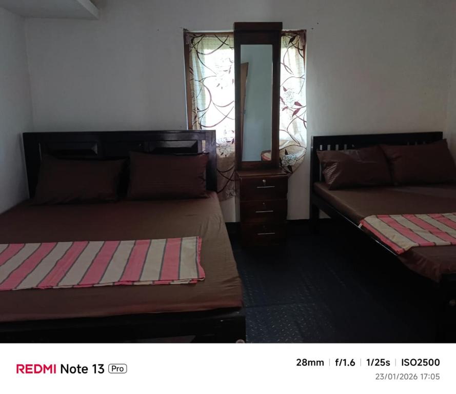 a bedroom with two beds and a dresser and a mirror at New Guest in Nilaveli