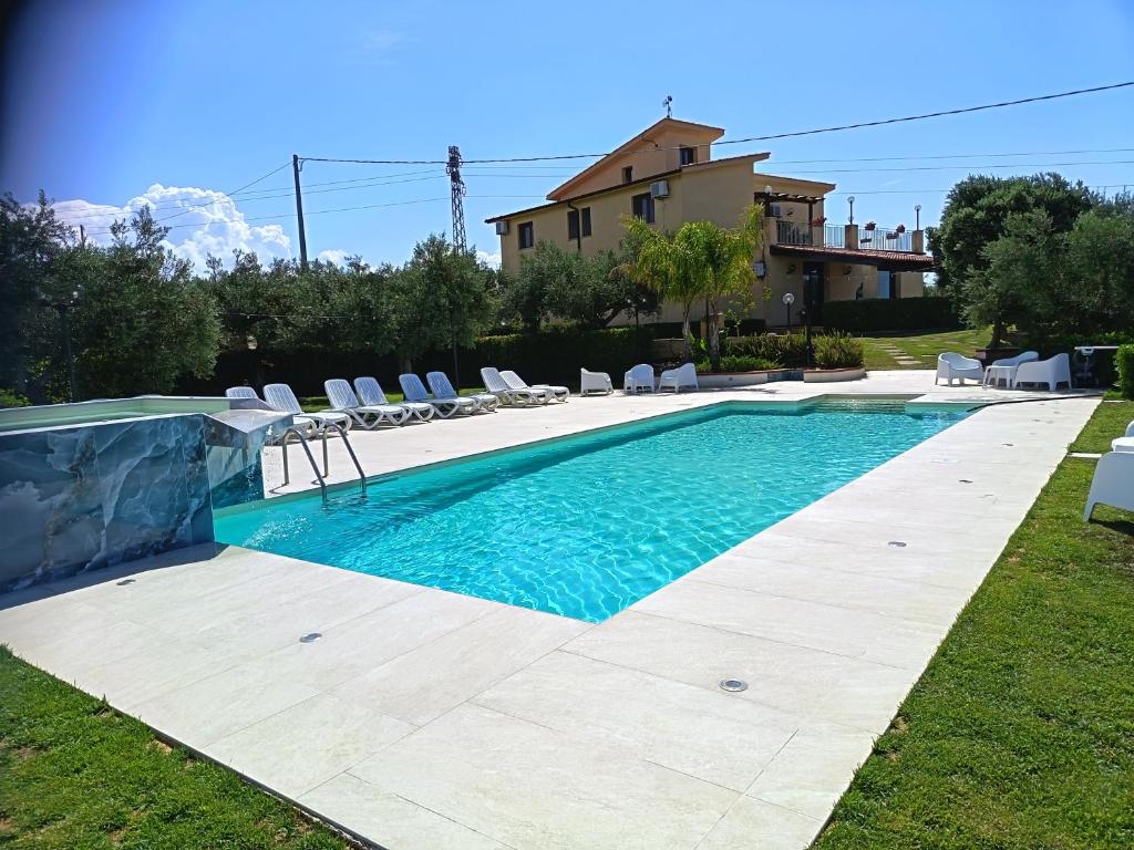 a swimming pool with chairs and a house at B&B Le Foglie D'Argento in Caltabellotta