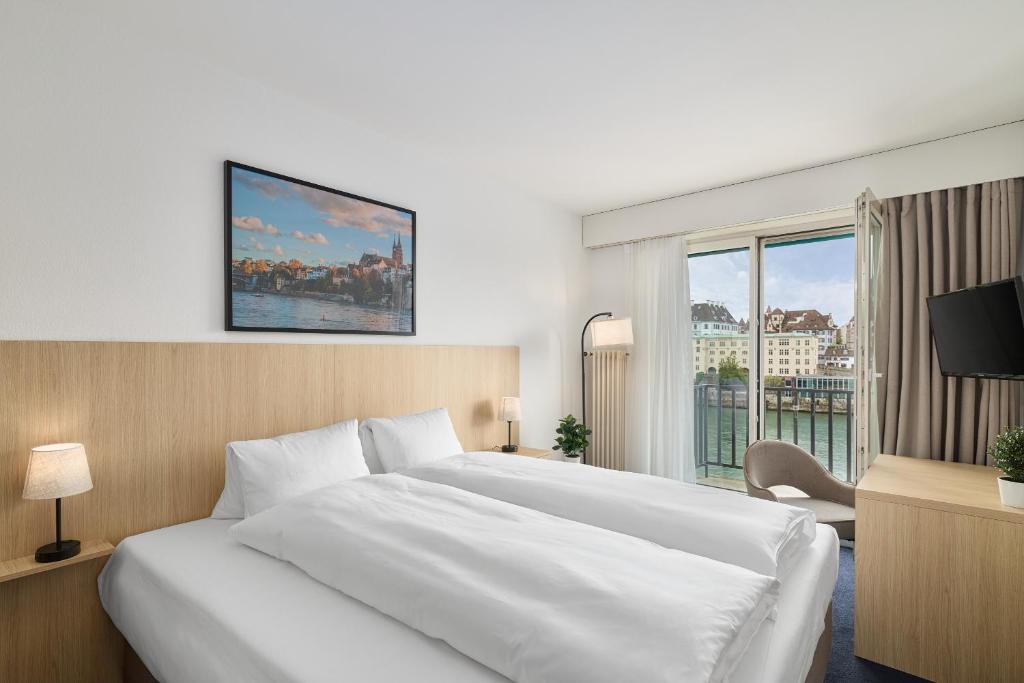 a bedroom with a large white bed and a window at Riverside Hotel Merian - opening 2026 in Basel