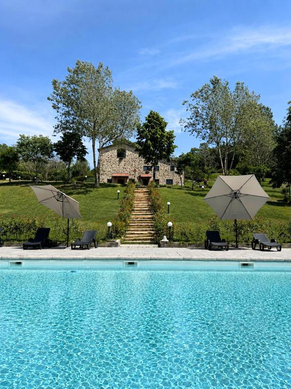 a swimming pool with two umbrellas and a house at Tenuta Valdea in Firenzuola