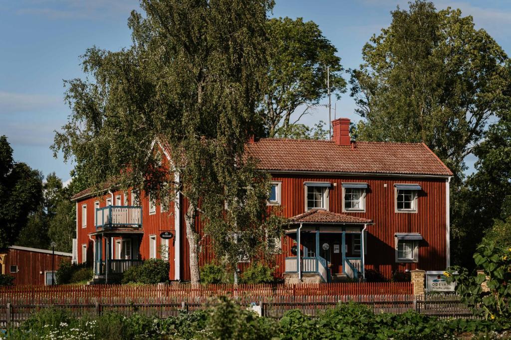 a red house with a tree in front of it at Ödevata Gårdshotell in Emmaboda