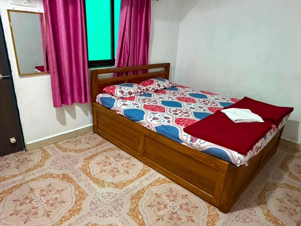 a bedroom with a bed and a window with pink curtains at SH Guest House Malvan in Malvan