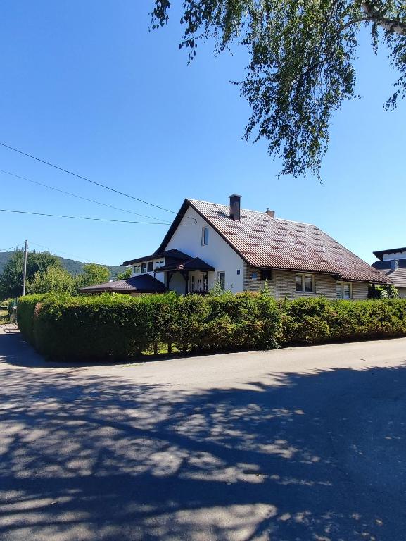 a white house with a red roof on a street at Apartman Sunce in Ogulin