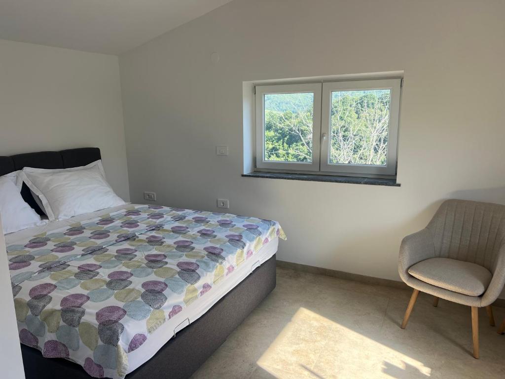 a bedroom with a bed and a chair and a window at Olive Garden Studio in Izola