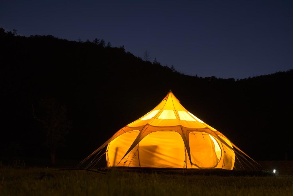 a lit up tent in a field at night at Old Mill Glamp in Kozov