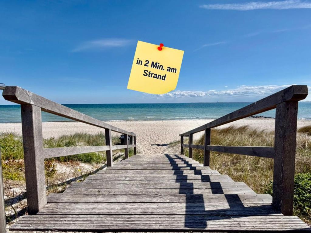 a boardwalk leading to the beach with a sign at Wahlheimat Haffkrug, Strandnaher Ostseeurlaub, Terrasse, Tiefgarage und WLAN in Scharbeutz