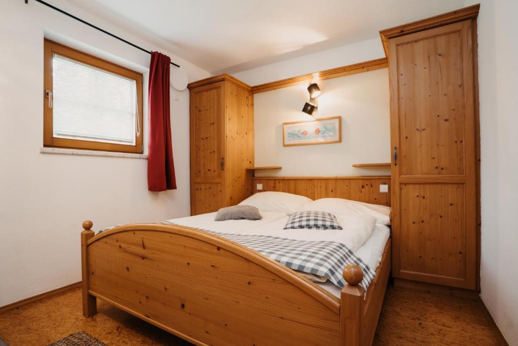 a bedroom with a wooden bed and a window at Gästehaus Berger in Tröpolach